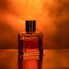 Szklana buteleczka perfum z bursztynowym płynem, emanująca ciepłym, zmysłowym amber zapach.