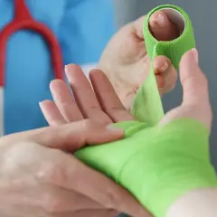 Lekarz opatruje rękę po urazie, być może po wybitym palcu. RTG potwierdzi diagnozę.