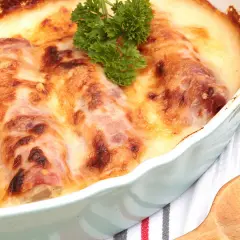 Escalope savoyarde gratinée, dorée et savoureuse, garnie d'une touche de persil frais. Un délice réconfortant.