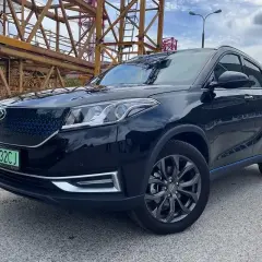Czarny, lśniący SUV, jeden z chińskich samochodów elektrycznych, zaparkowany na tle budowy.