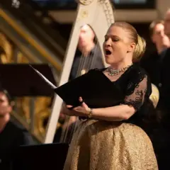 Sångerska med gyllene kjol framför en harpa under Stockholm Early Music Festival.