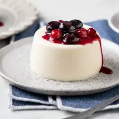 Panna cotta bianca con topping di frutti di bosco e salsa rossa. Ingredienti panna cotta freschi e invitanti.