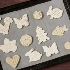 Figurki z masy solnej: kogut, motyl, królik, choinka, ryba, serce i kwiaty czekają na pieczenie.
