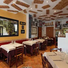 Interno di un'accogliente osteria a Bologna, con tavoli apparecchiati e un soffitto decorato con tappi di sughero.