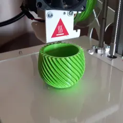 Drukarka 3D drukuje zielony, spiralny wazon.