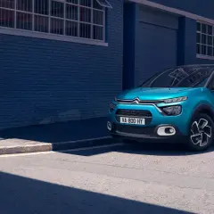 Citroën C3 bleue garée sur le trottoir, avec un panneau de signalisation. La taille pneu Citroën C3 est adaptée à ce modèle urbain.