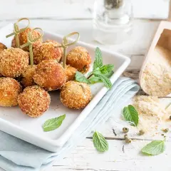Deliziose polpette tonno e ricotta, dorate e croccanti, servite su un piatto bianco con menta fresca.