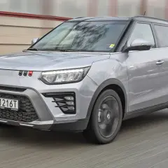 Srebrny SsangYong Tivoli z czarnym dachem pędzi po drodze.