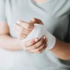 Dłoń z bandażem, wspierająca proces gojenia ran. Odpowiednia dieta na gojenie ran przyspieszy powrót do zdrowia.