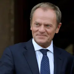 Uśmiechnięty Donald Tusk w granatowym garniturze i krawacie w kropki. Czy Tusk zna angielski? Pewnie tak, w końcu to polityk europejski!