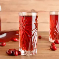 Szklanka i butelka z nalewką z derenia. Na drewnianym blacie leżą owoce derenia. Idealny przepis na nalewkę z derenia.