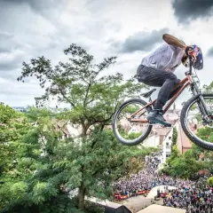Kolarz w powietrzu na rowerze, idealnym na pumptrack, nad tłumem widzów.