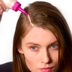 Mujer se aplica tinte en el cabello. Considera los tintes con amoniaco: ventajas y desventajas antes de usarlos.