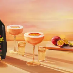 Passoa to alkohol z marakui. Butelka likieru, drinki i świeże owoce na tle zachodzącego słońca.