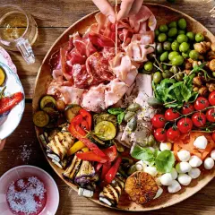 Eine üppige antipasti platte mit Wurst, Käse, Oliven, gegrilltem Gemüse und Tomaten.