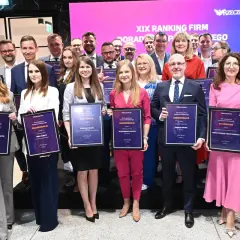 Grupa osób w eleganckich strojach pozuje z dyplomami na tle sceny z logo "Rzeczpospolita".