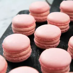 Rosa macarons på en mörk yta, perfekta för ett macarons recept.