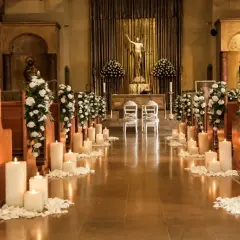 Eleganckie strojenie kościoła na ślub: białe kwiaty, płatki róż i mnóstwo świec tworzą romantyczną atmosferę.