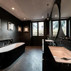 Elegantes, dunkles Badezimmer mit freistehender schwarzer Wanne, Doppelwaschbecken und moderner Spiegelarchitektur.