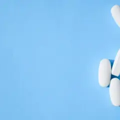 Białe tabletki, w tym oxycodone, wysypują się z przezroczystego pojemnika na niebieskim tle.