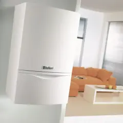 Nowoczesny, biały piec z zamkniętą komorą spalania marki Vaillant, dyskretnie zamontowany na ścianie w salonie.