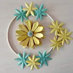 Kreative Blumen aus Eierkarton, gelb und türkis, um einen weißen Ring arrangiert.