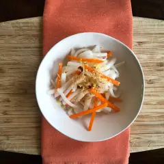 A refreshing namasu recipe with julienned daikon radish and carrots, seasoned with sesame seeds and a hint of citrus zest.