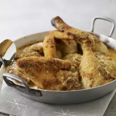 Un plat de poulet Gaston Gérard gratiné, doré et croustillant, servi dans un plat en métal avec une cuillère.