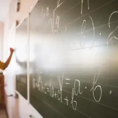 Nauczycielka pisze wzory matematyczne na tablicy. To jak art 20 kn, gdzie każdy symbol ma swoje znaczenie.