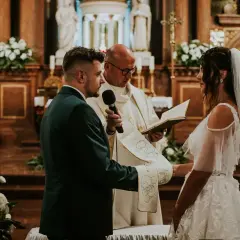 Para młoda i pan młody podczas ceremonii, łączącej ślub kościelny i cywilny razem. Ksiądz czyta z księgi.