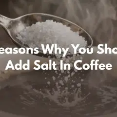 En sked med salt hälls ner i en ångande kaffekopp. Texten "5 Reasons Why You Should Add Salt In Coffee" syns tydligt.