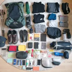 Packliste Jakobsweg: Rucksack, Wanderschuhe, Kleidung, Wasserflasche, Wanderstöcke, Reiseführer und weitere Essentials für den Pilgerweg.