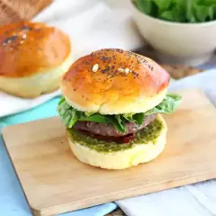 Pyszny burger włoski z soczystym mięsem, świeżą sałatą i aromatycznym pesto na złocistej bułce z makiem.