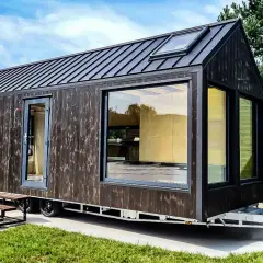 Nowoczesny tiny house w Polsce, z ciemną drewnianą elewacją i dużymi oknami, gotowy na przygodę.