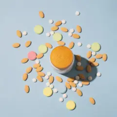 Pilules contraceptives et autres comprimés colorés dispersés autour d'un pot. Une solution pour l'acné ?