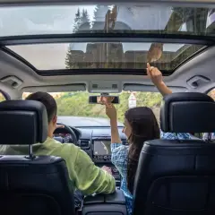 Familie im Auto mit Panoramadach. Die Sonne scheint durch das Fenster, hoffentlich kein Sonnenbrand!
