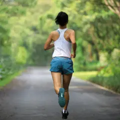 Kobieta biegnie leśną drogą. Czy bieganie to cardio? Zdecydowanie tak! To świetny trening dla serca.