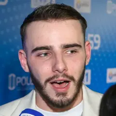 Krystian Ochman, z żoną u boku, pozuje na tle niebieskiej ścianki z logo TVP 1 i Opole 59.