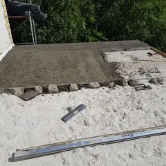 Budowa dachu z wykorzystaniem styrobetonu. Widać świeżo wylany materiał i narzędzia budowlane.