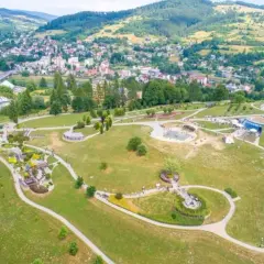 Malowniczy park z alejkami, placem zabaw i wodnymi atrakcjami. W tle widać miasto i góry. To świetne miejsce na rodzinne wycieczki, odkrywając nowe atrakcje Nowego Sącza.