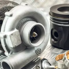 Turbosprężarka i tłok marki Kolbenschmidt na metalowej powierzchni.