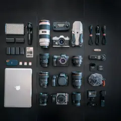 A filmmaker's dream setup, showcasing a serious case of gear acquisition syndrome: cameras, lenses, drone, laptop, and audio gear laid out.