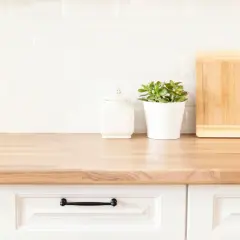 Drewniany blat kuchenny, ozdobiony słoiczkiem, doniczką z rośliną i deskami do krojenia. Dowiedz się, jak odnowić blat kuchenny z mdf.