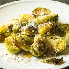 Pyszna sałatka z brukselką, pieczona z parmezanem i oliwą, podana na białym talerzu.