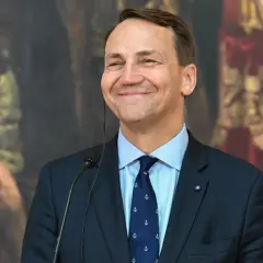 Uśmiechnięty Sikorski, który polityk? W tle obraz z postaciami.