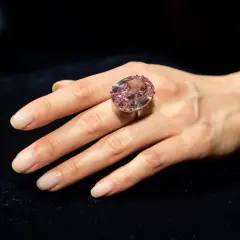 Ein großer, ovaler rosa Diamantring, der den teuersten Diamant der Welt Preis repräsentiert, wird an einer Hand getragen.