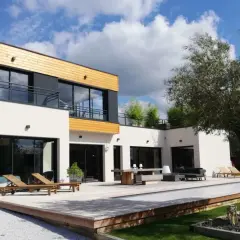 Maison moderne avec piscine et terrasse en bois. On se demande combien de m3 d'eau pour construire une maison comme celle-ci.