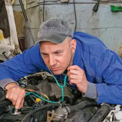 Mechanik z wyspecjalizowanym stetoskopem nasłuchuje pracy silnika, sprawdzając, czy tłoki działają prawidłowo.