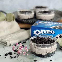 Leckeres Oreo Rezept: Cremige Desserts im Glas, garniert mit zerbröselten Keksen und frischen Kräutern.