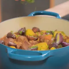 Un plat mijoté de navarin d'agneau, avec des morceaux de viande tendres, des carottes, des oignons rouges et des pommes de terre, garni de persil frais.